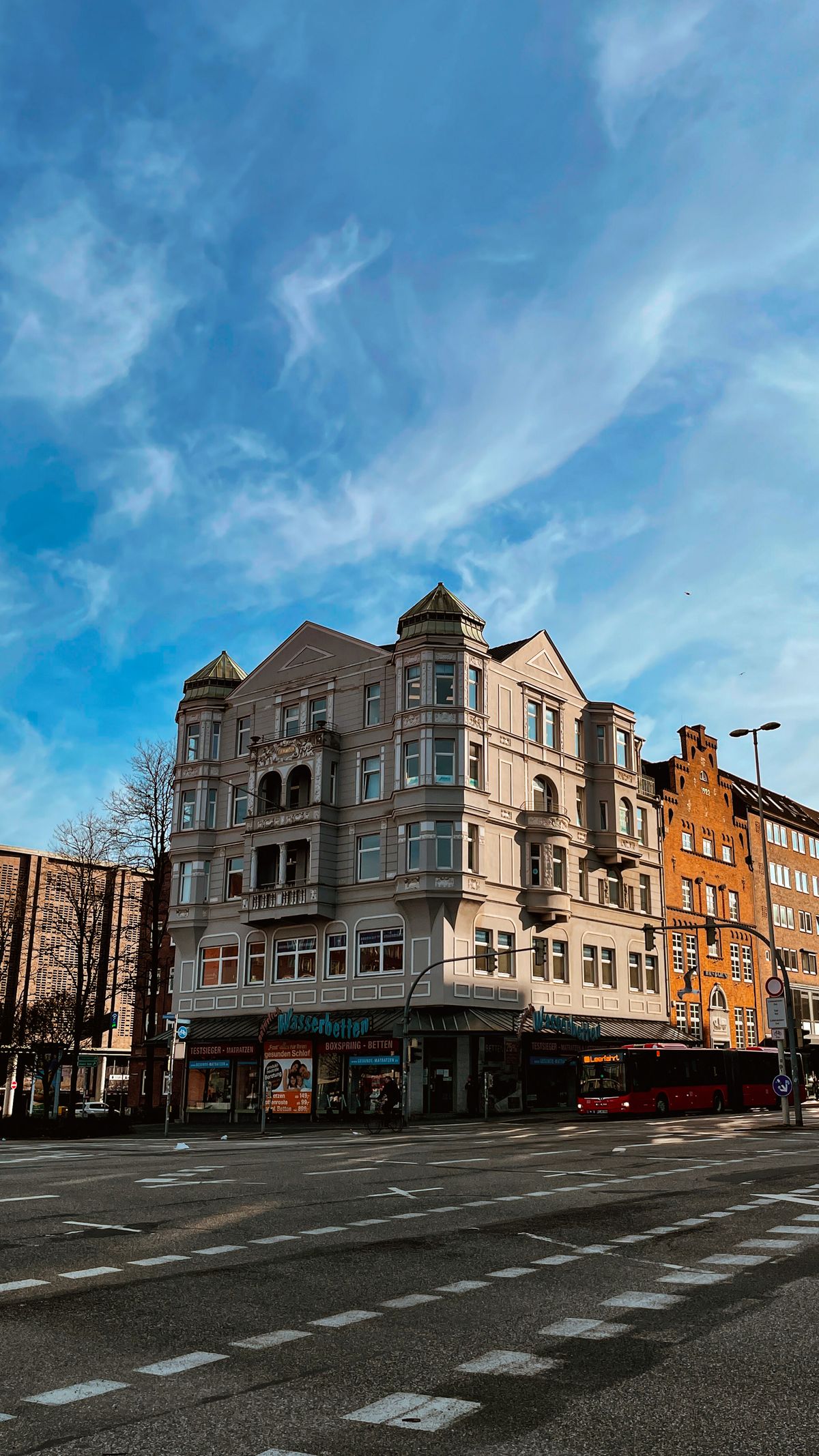 Straßenkreuzung in Kiel mit Gründerzeit-Wohnhaus und Ladenzeile